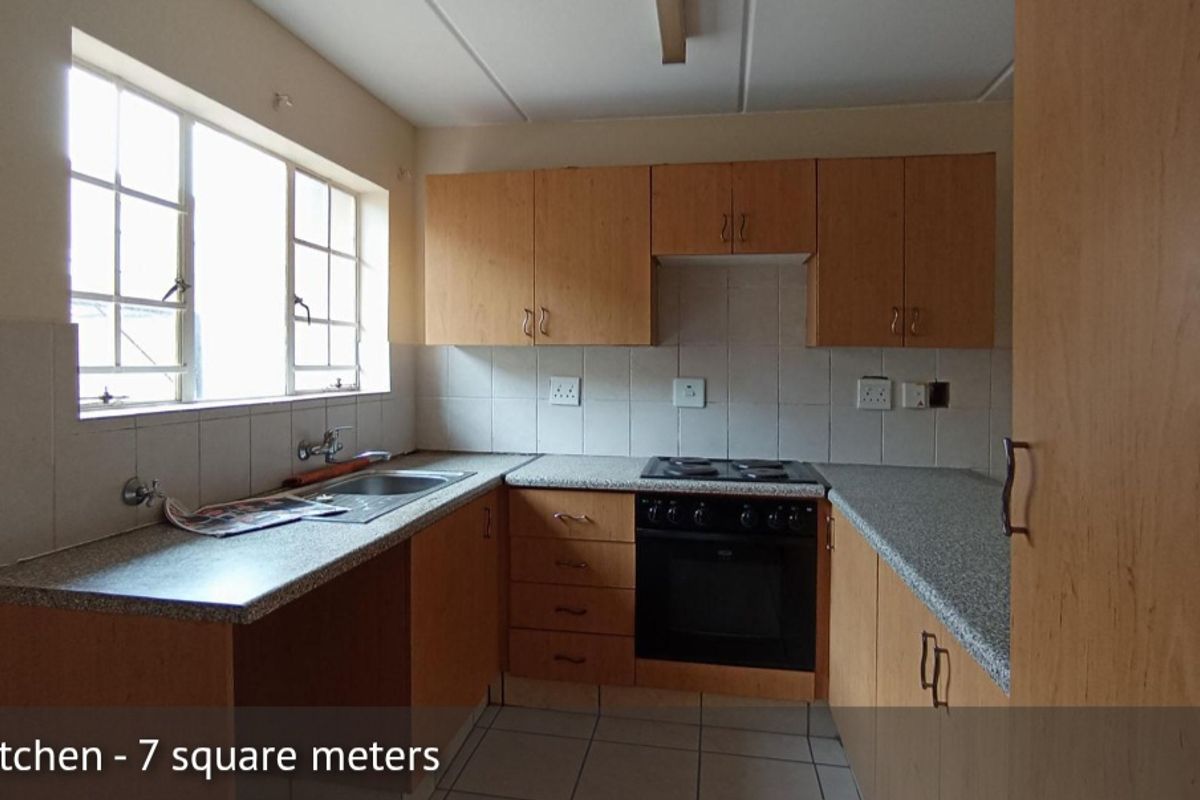 A functional, compact kitchen featuring built-in wooden cabinetry, laminate countertops, a built-in oven with electric hob, and tiled backsplash.