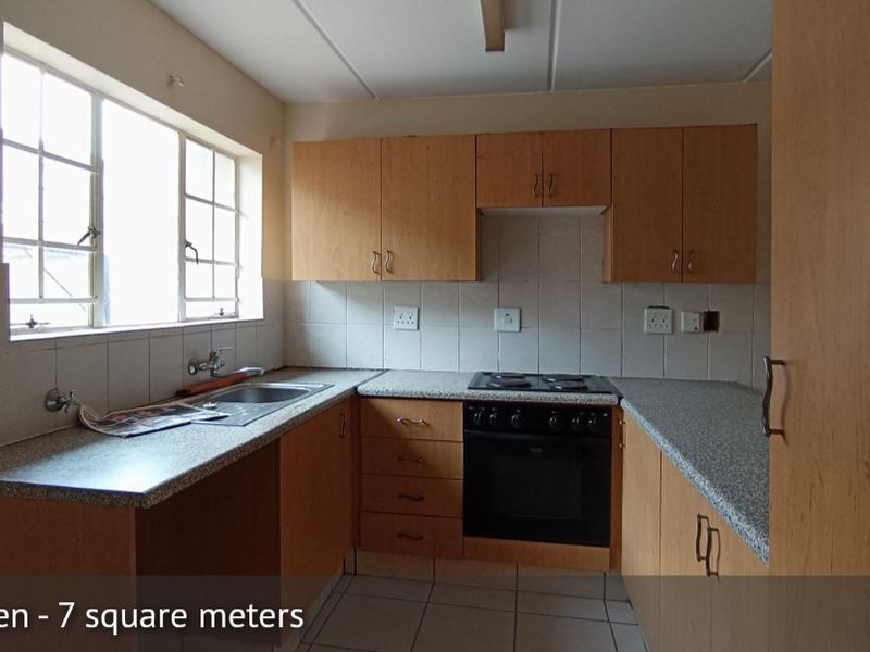 A functional, compact kitchen featuring built-in wooden cabinetry, laminate countertops, a built-in oven with electric hob, and tiled backsplash.