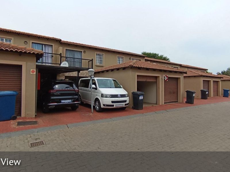 Front elevation of a townhouse complex featuring multiple garage units, tiled roofing, and paved driveway access.