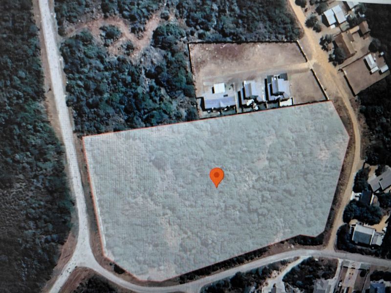 An aerial view of a vacant residential plot of land, showing its boundaries and surrounding vegetation.
