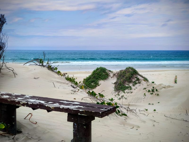 A scenic view of the ocean and sandy beach dunes, showcasing the natural coastal landscape of the property.