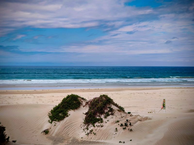 A scenic view of the sandy beach, dunes, and ocean, highlighting the natural coastal landscape of the property.