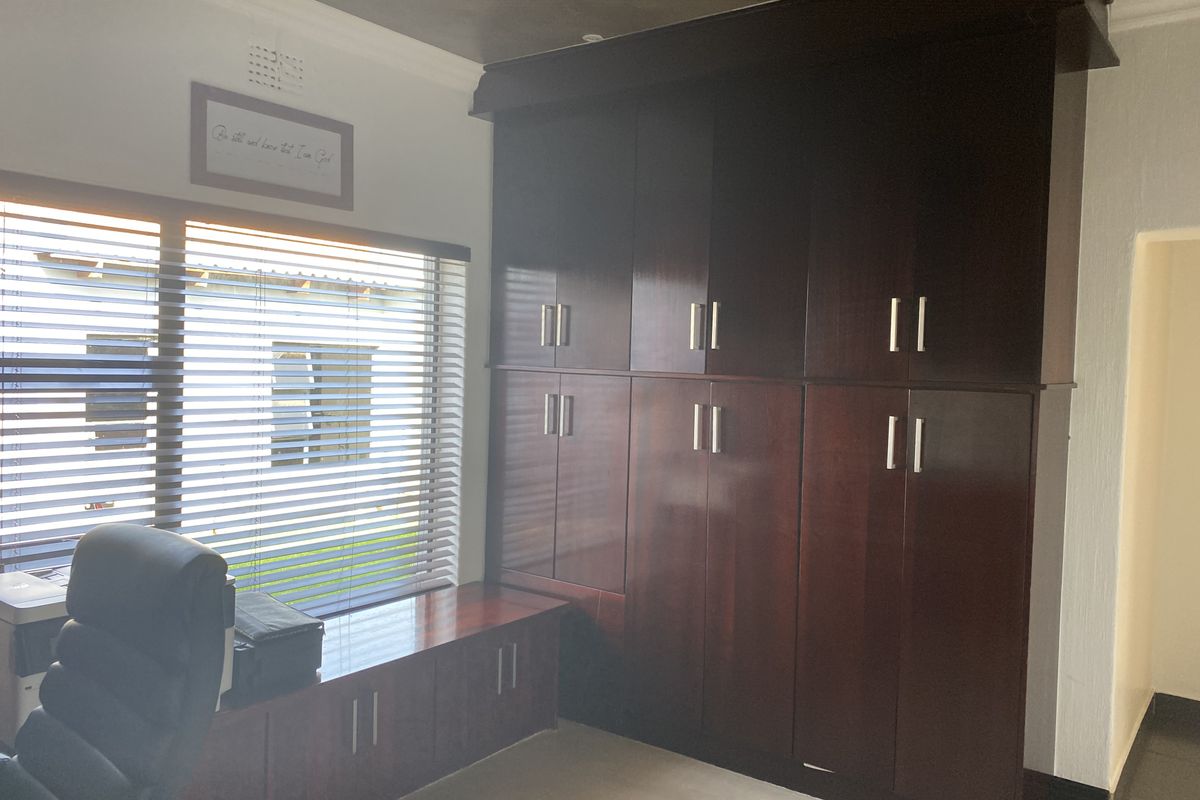 A bedroom featuring extensive dark wood built-in cabinetry providing ample storage space and horizontal window blinds.