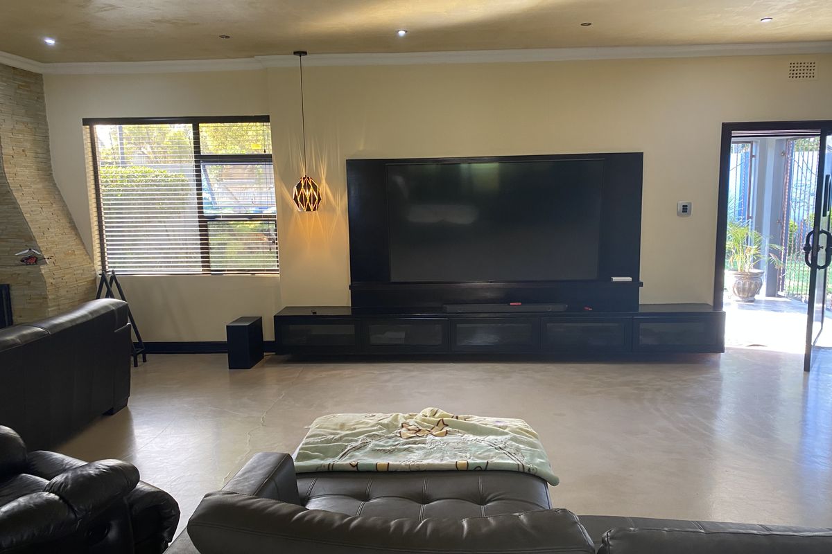 Spacious living room featuring polished concrete floors, a stone feature wall, and a large built-in media console with integrated storage.