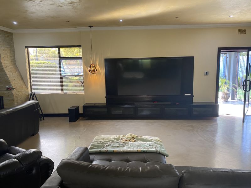 Spacious living room featuring polished concrete floors, a stone feature wall, and a large built-in media console with integrated storage.