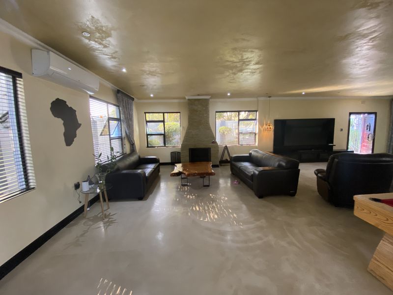 Spacious living room featuring polished concrete floors, a central stone-clad fireplace, and a wall-mounted split-system air conditioner.