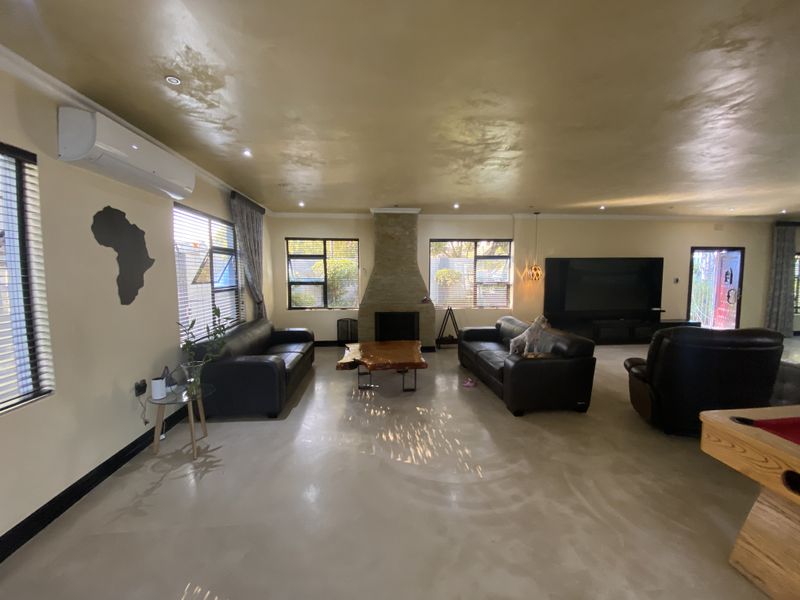 Spacious living room featuring polished concrete floors, a stone-clad fireplace, and a wall-mounted air conditioning unit, offering a modern and open layout.
