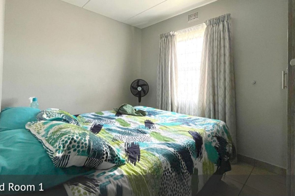 A standard bedroom featuring tiled flooring, a window with curtain tracks, and a ceiling ventilation vent.