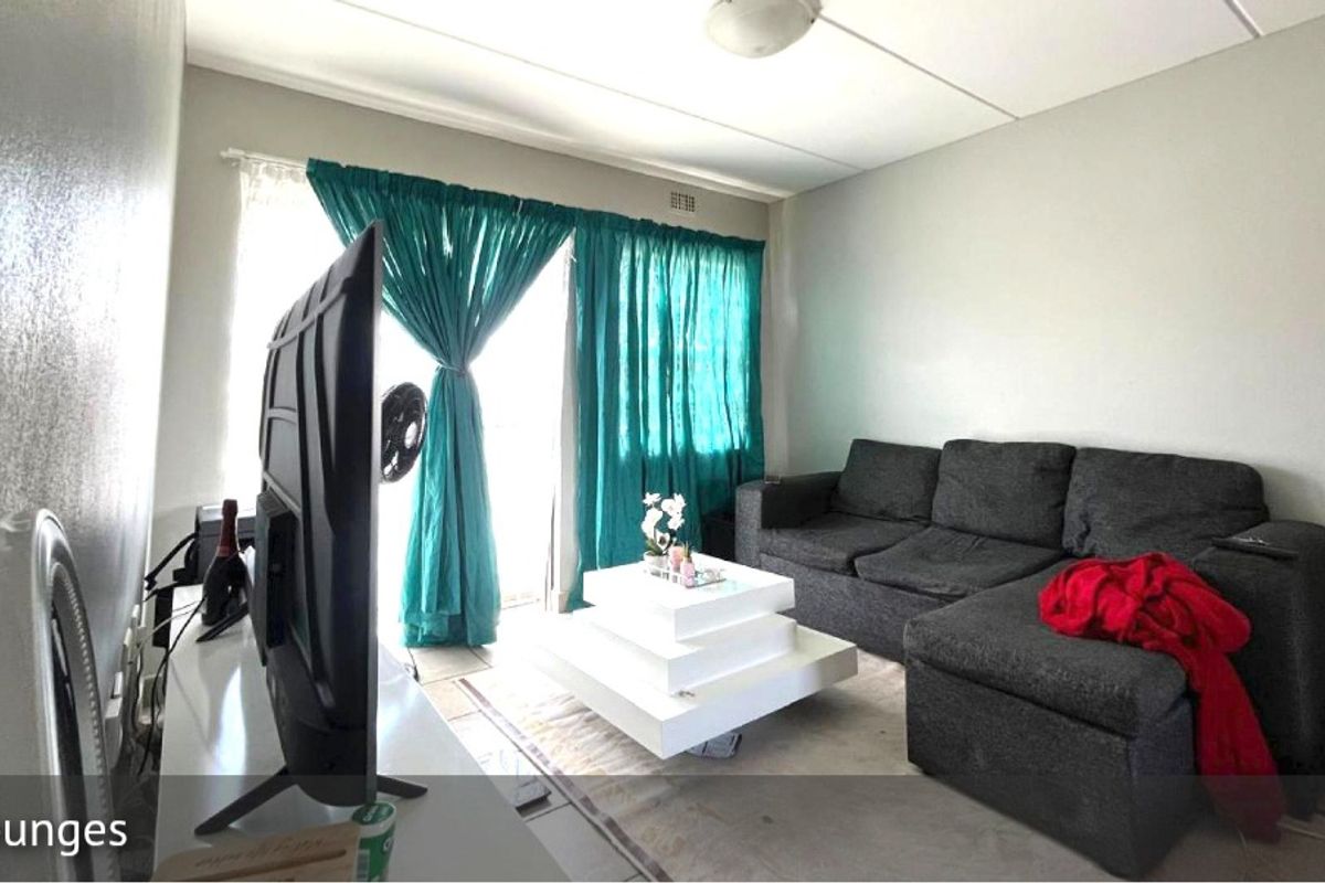 A living room featuring tiled flooring, a sliding glass door with curtains, and a ceiling-mounted light fixture.