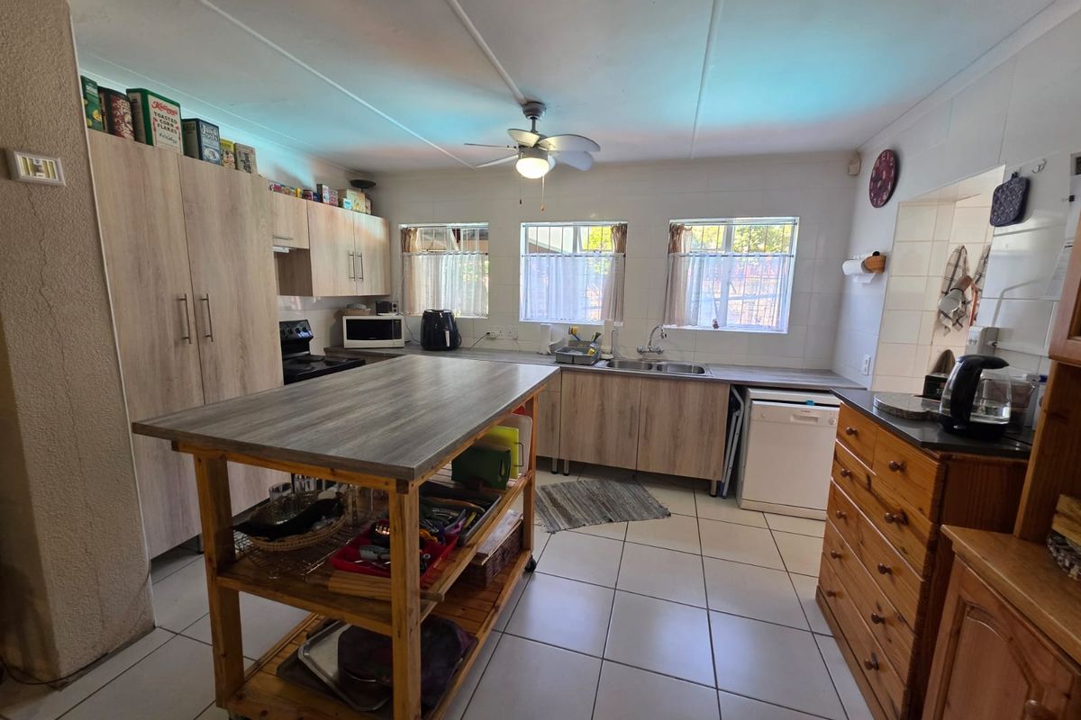 Functional kitchen featuring light wood-look cabinetry, tiled flooring, double sink, and a central island workspace with ample storage.