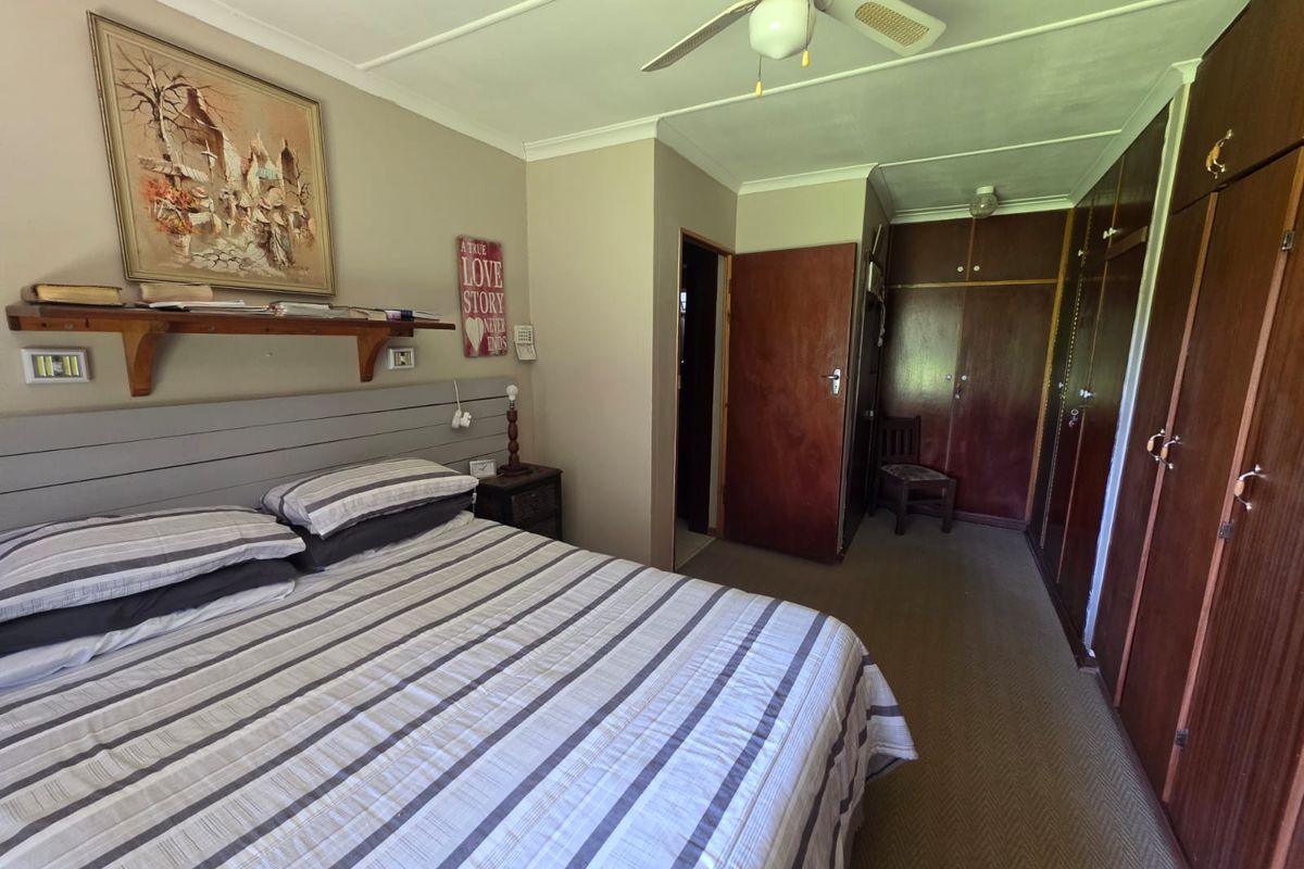 A bedroom featuring built-in wooden wardrobes, a ceiling fan, and carpeted flooring.