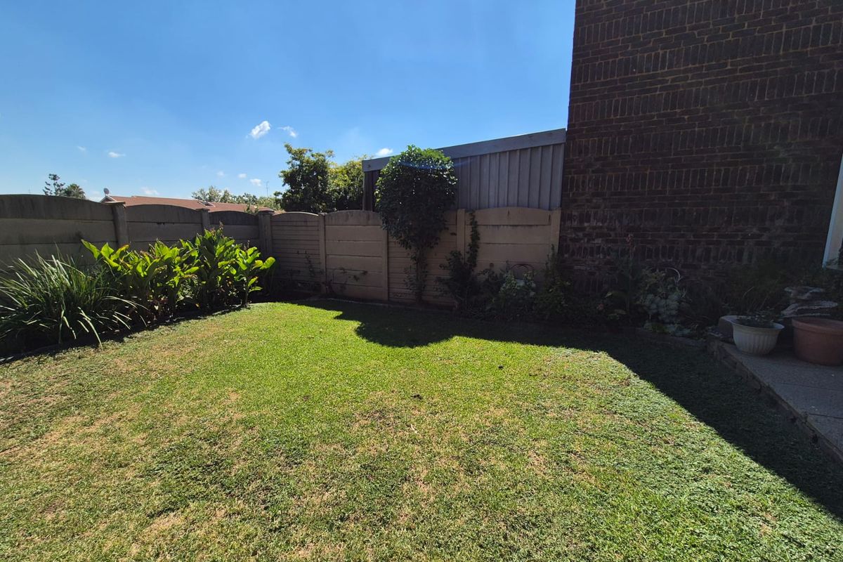 A private rear garden featuring a grass lawn and perimeter boundary wall, adjacent to the townhouse brick exterior wall.