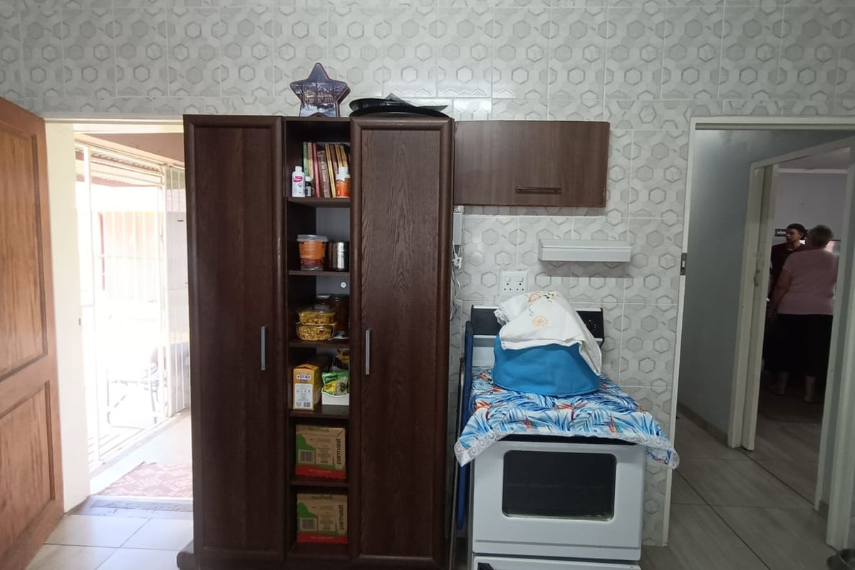 A functional kitchen area featuring tiled walls, built-in cabinetry, and a freestanding stove, providing a practical layout for daily meal preparation.
