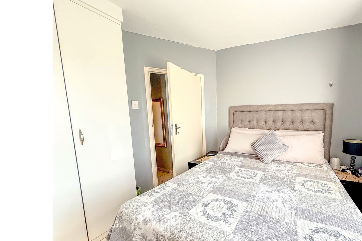 A functional bedroom featuring a built-in white wardrobe and neutral wall tones, providing a clean and simple living space.