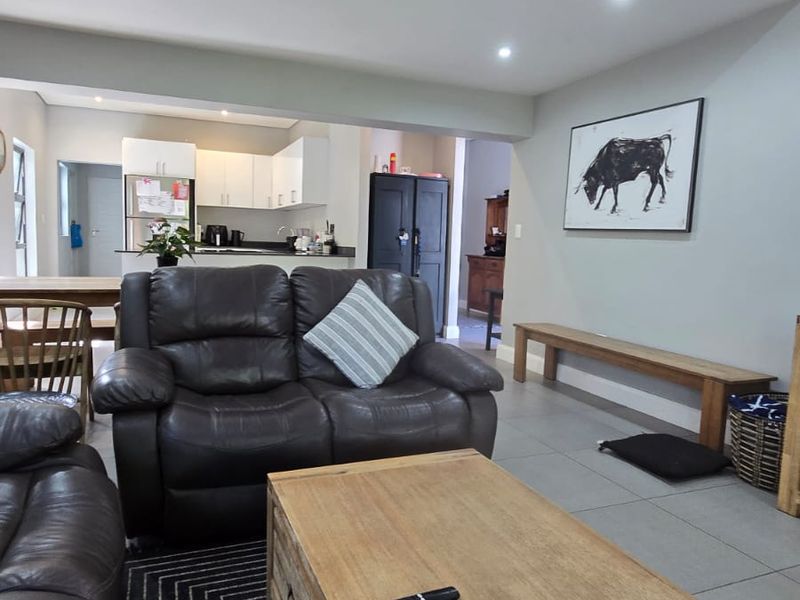 An open-plan living area featuring tiled floors, recessed lighting, and a view through to the kitchen space.