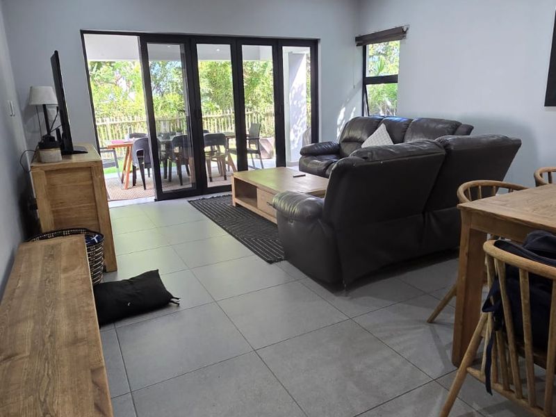 Spacious living area featuring modern tiled flooring, recessed downlighting, and large aluminium sliding doors providing seamless access to the outdoor patio.