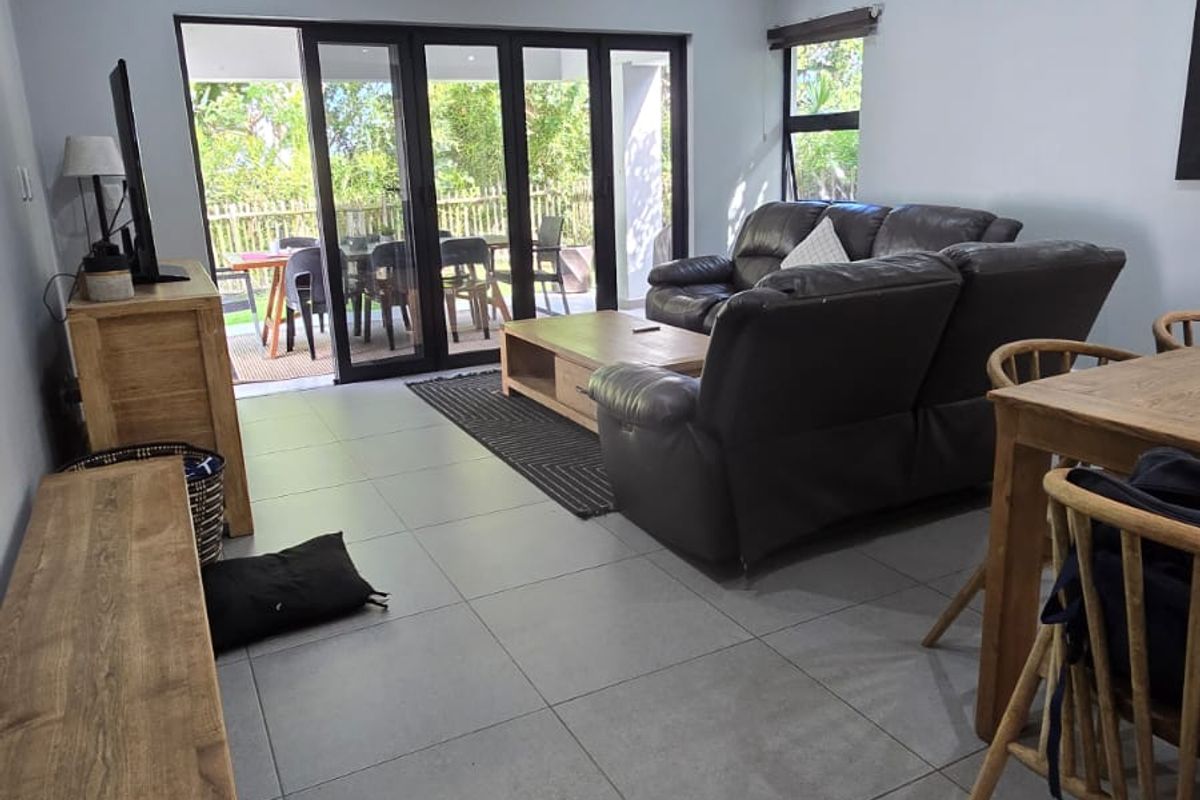 Spacious living area featuring modern tiled flooring, recessed downlighting, and large aluminium sliding doors providing seamless access to the outdoor patio.