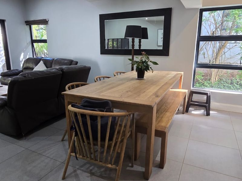 Open plan living and dining area featuring large format floor tiles, recessed downlighting, and large windows providing natural light.