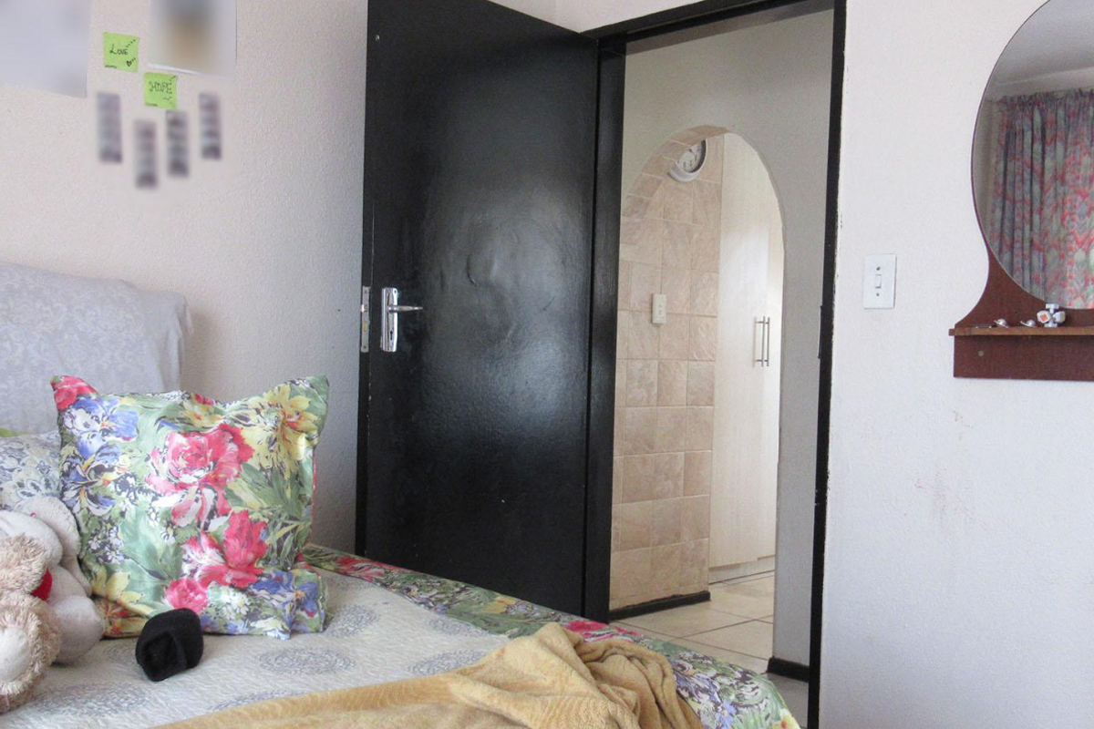 A bedroom featuring a black interior door leading to an adjacent tiled space with an arched doorway.