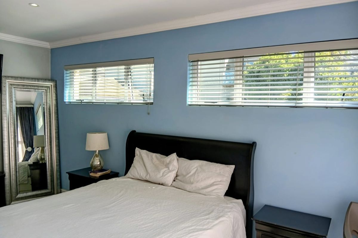 A bedroom featuring blue painted walls, horizontal window blinds, and recessed ceiling lighting.