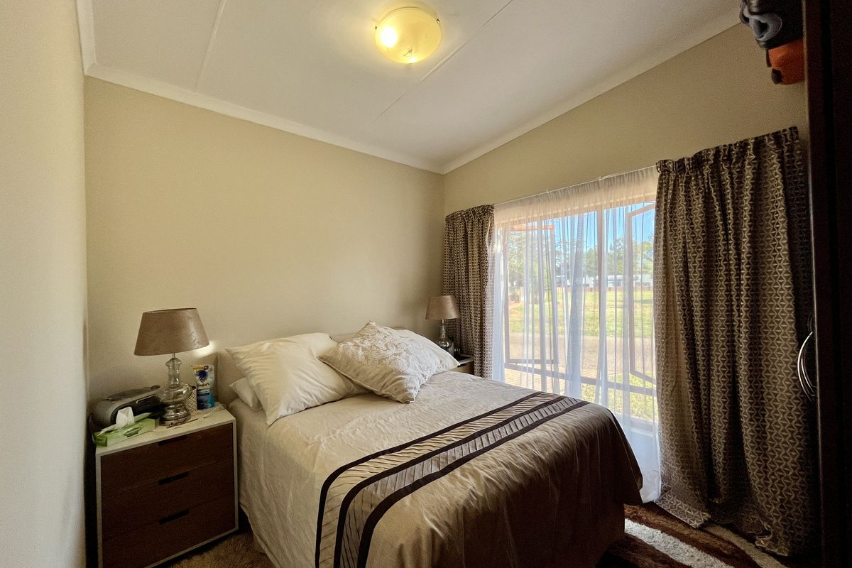 A cozy bedroom featuring a large window with curtains, providing natural light and a view of the exterior.