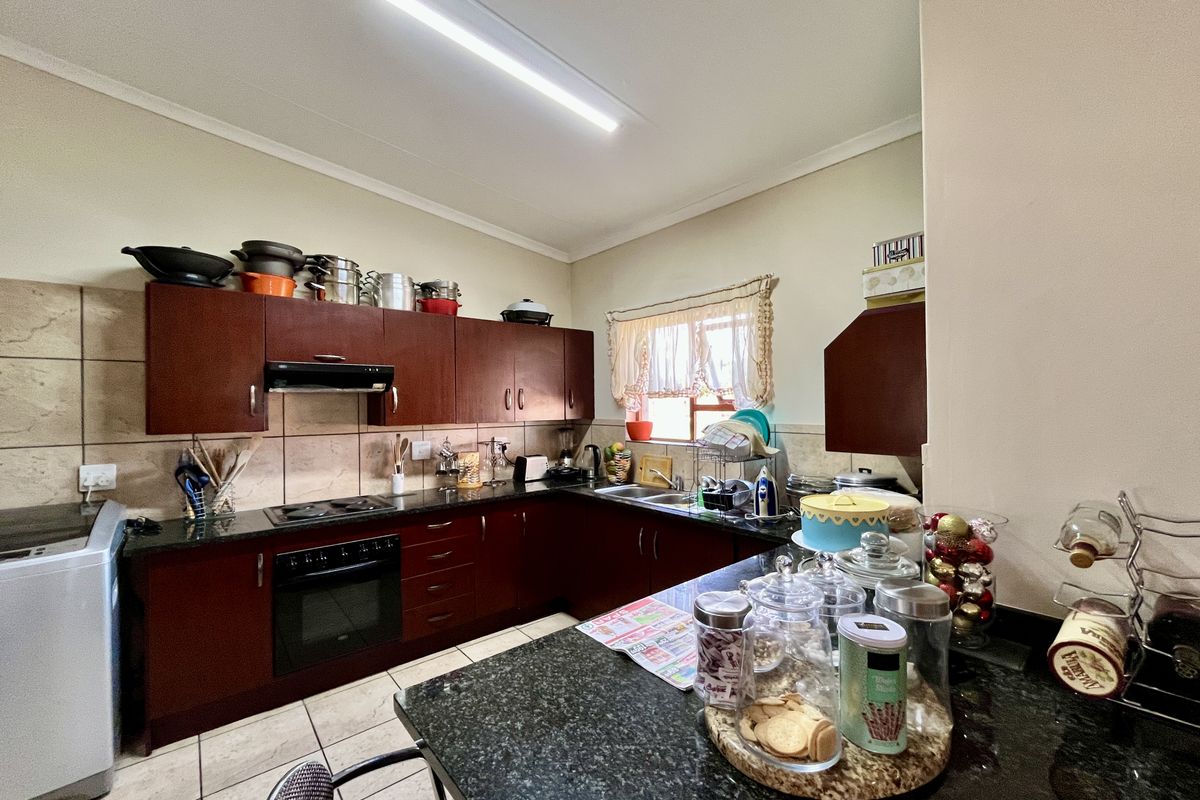 Functional kitchen featuring dark wood cabinetry, granite countertops, integrated oven and hob, and a breakfast nook area.