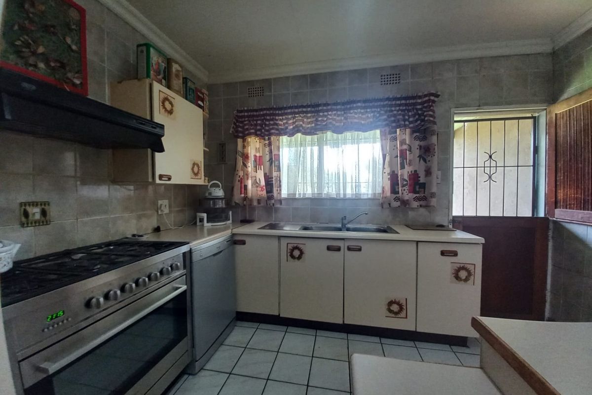 Functional kitchen featuring tiled walls and flooring, built-in cabinetry, stainless steel gas stove with extractor fan, and direct access to the exterior.