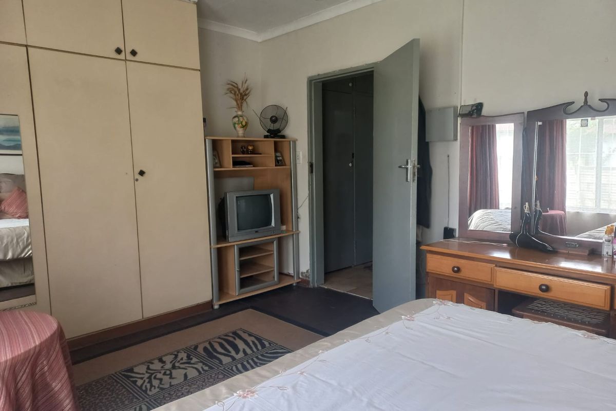 A bedroom featuring built-in floor-to-ceiling cupboards, neutral walls, and a doorway leading to an adjacent space.