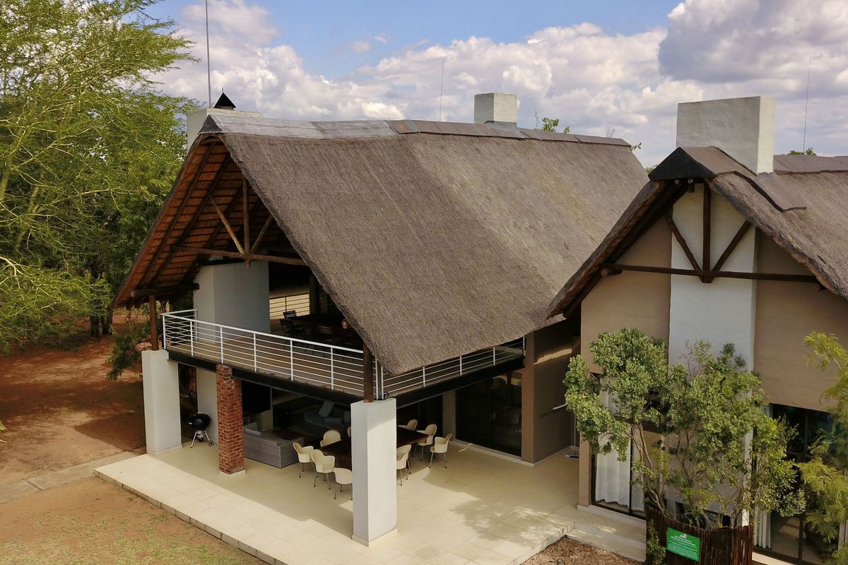 Aerial view of a lodge featuring a traditional thatched roof, expansive covered patio, and open-plan living areas with integrated structural design.