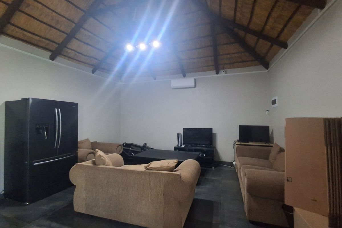 Spacious living area featuring a high vaulted thatched ceiling, exposed timber beams, and tiled flooring, creating a rustic yet comfortable atmosphere.