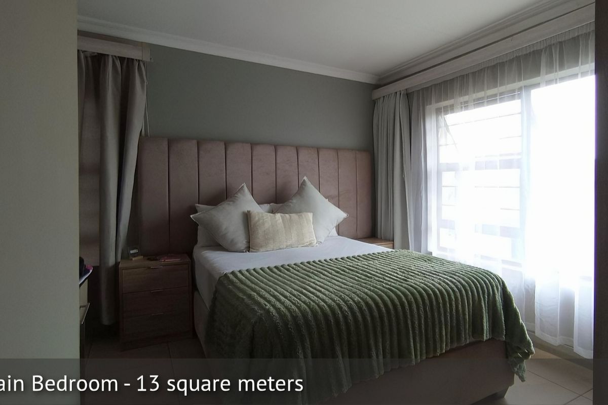 A well-proportioned bedroom featuring neutral wall tones, tiled flooring, and large windows that provide ample natural light.