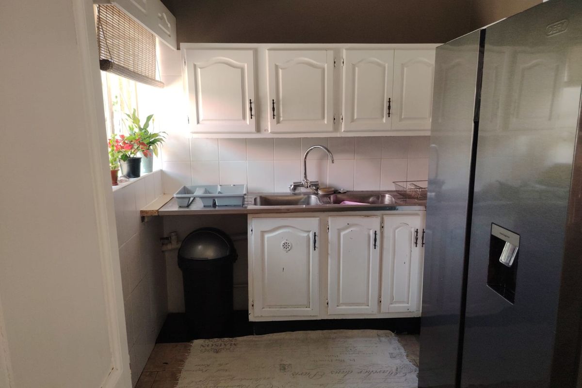 A functional kitchen area featuring white cabinetry, a double stainless steel sink, and tiled backsplash.