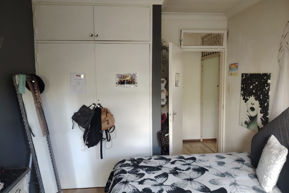 A bedroom featuring built-in floor-to-ceiling cupboards with overhead storage and a doorway leading to an adjacent hallway.