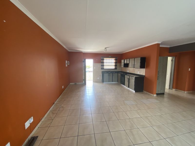 Open-plan living and kitchen area featuring tiled flooring, built-in cabinetry, and integrated appliances, offering a functional space ready for personalization.