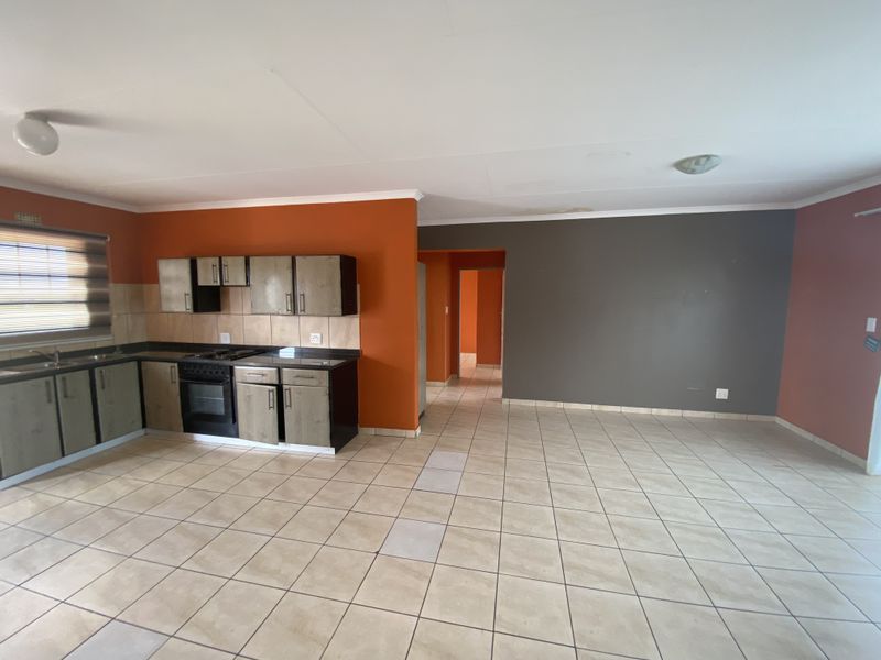 Open-plan kitchen and living area featuring tiled flooring, built-in cabinetry, and a built-in oven, offering a functional space ready for personalization.