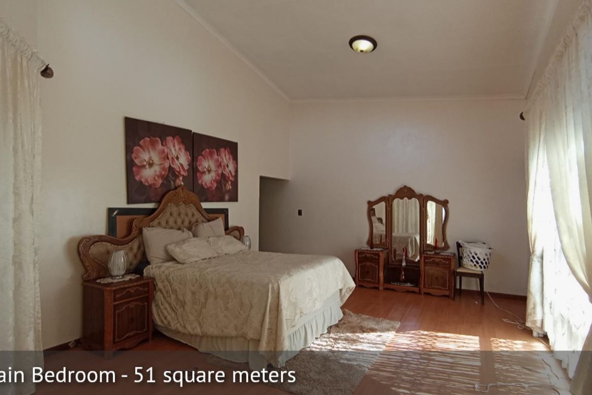 Spacious main bedroom featuring high ceilings, laminate flooring, and large windows allowing for ample natural light.