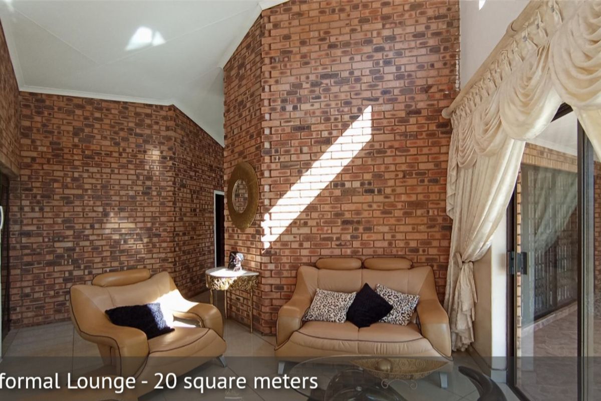 Spacious informal lounge featuring high vaulted ceilings and a prominent exposed face-brick feature wall with large sliding glass doors leading to the patio.