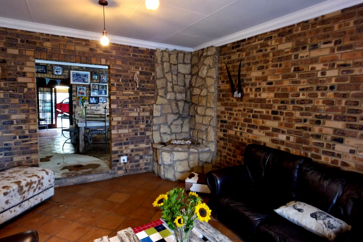 A rustic living room featuring exposed brick walls, a stone fireplace, and terracotta floor tiles, offering a warm and traditional aesthetic.