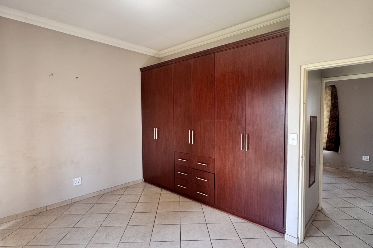 A bedroom featuring tiled flooring, built-in wooden cabinetry, and a doorway leading to an adjacent room.