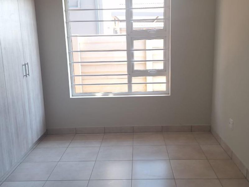 A clean, empty bedroom featuring neutral tiled flooring and modern built-in cupboards, providing a versatile space ready for personalization.