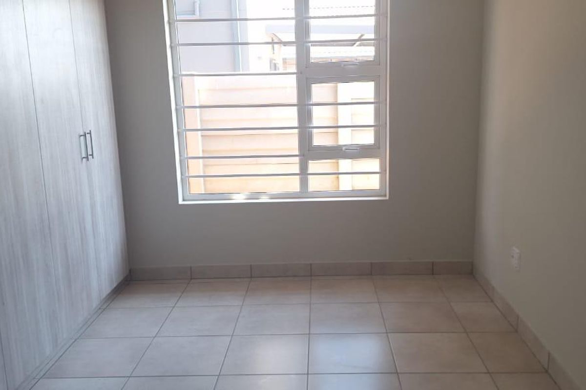 A clean, empty bedroom featuring neutral tiled flooring and modern built-in cupboards, providing a versatile space ready for personalization.