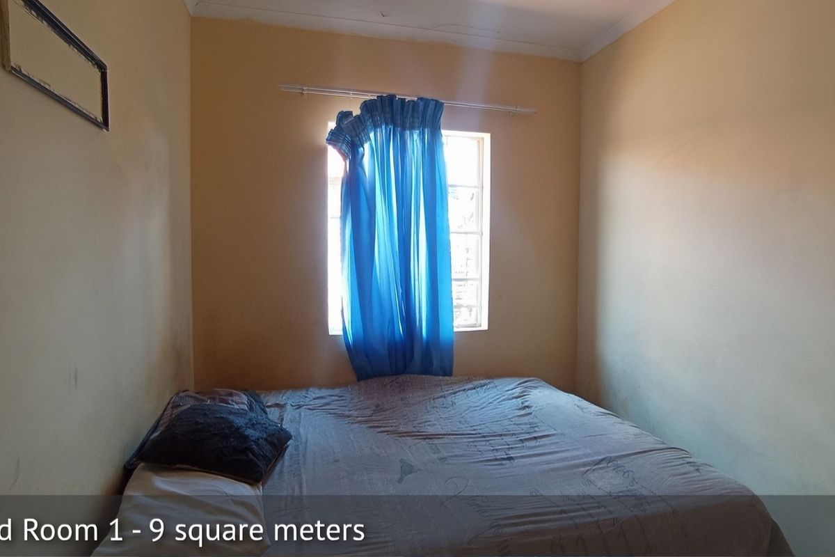 A compact bedroom featuring a window with curtain rail and standard wall finishes.