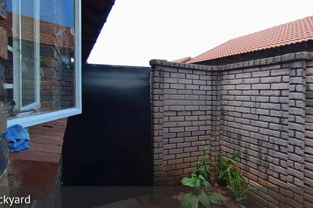 A private rear courtyard area featuring face-brick boundary walls and a secure metal gate, providing a secluded outdoor space.