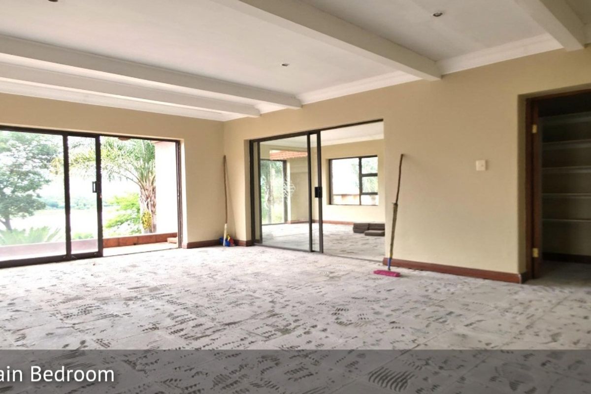 Spacious bedroom featuring large sliding glass doors leading to an outdoor area, recessed ceiling beams, and an integrated walk-in closet space.