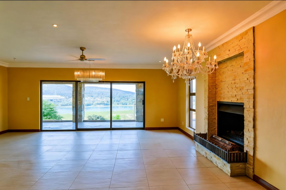 Spacious living area featuring a stone-clad fireplace, tiled flooring, and large sliding glass doors opening to a scenic outdoor view.
