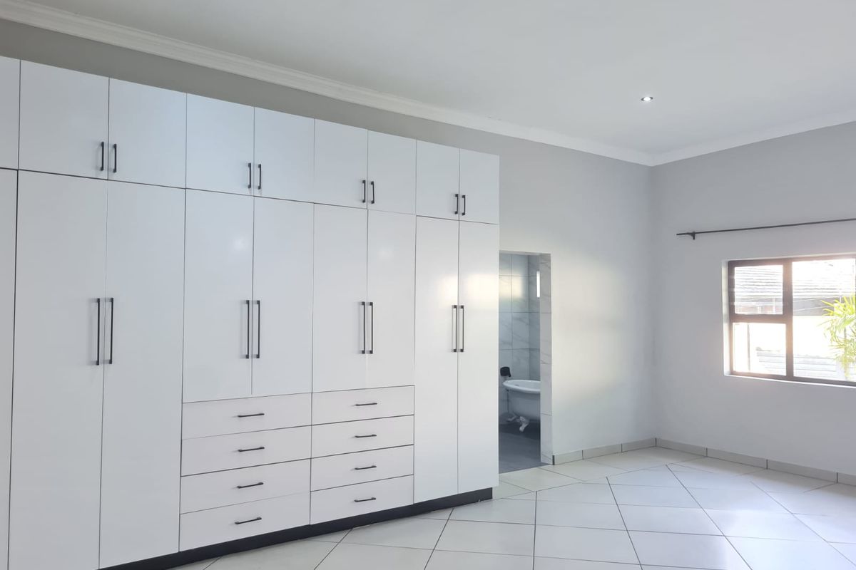 Spacious bedroom featuring extensive floor-to-ceiling built-in cabinetry, tiled flooring, and direct access to an en-suite bathroom.