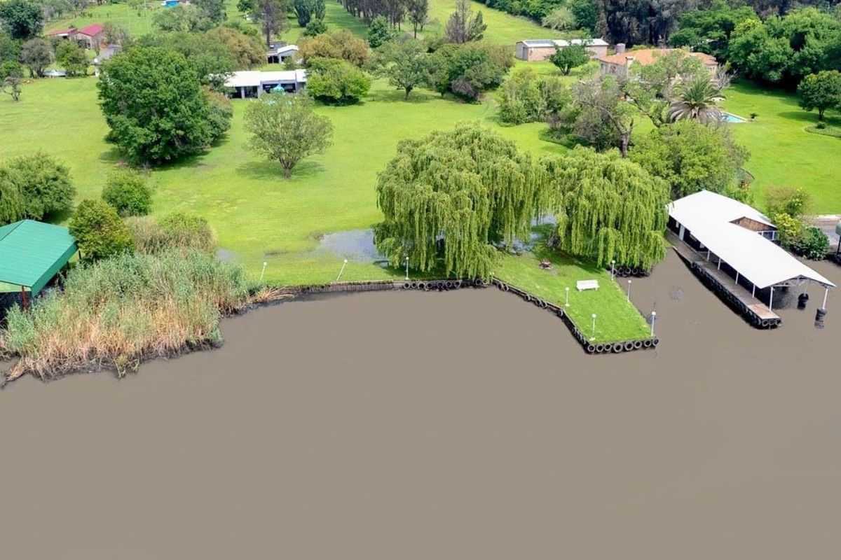 Aerial view of a waterfront property featuring boat houses, a landscaped garden, and direct access to the riverbank.