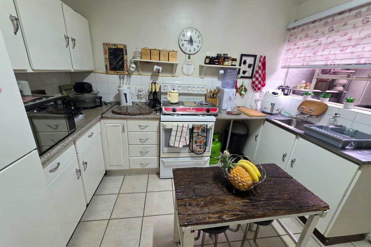 A functional kitchen featuring white cabinetry, granite-look countertops, a gas stove, and tiled flooring, offering a practical layout for daily meal preparation.