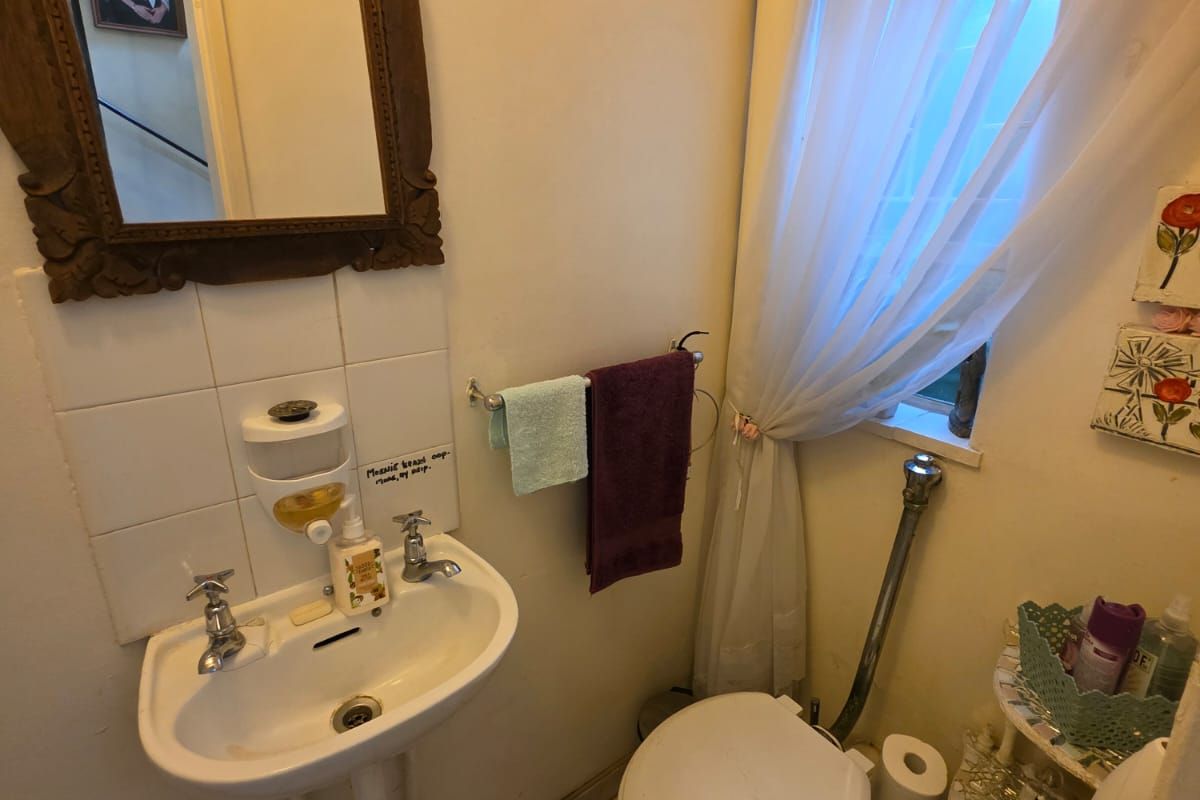 A compact guest bathroom featuring a wall-mounted basin, toilet, and tiled flooring, providing essential utility in a functional layout.