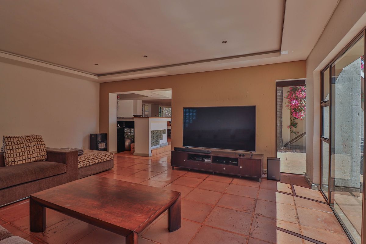 Spacious living area featuring terracotta floor tiles, recessed ceiling lighting, and large glass sliding doors providing access to the outdoor space.